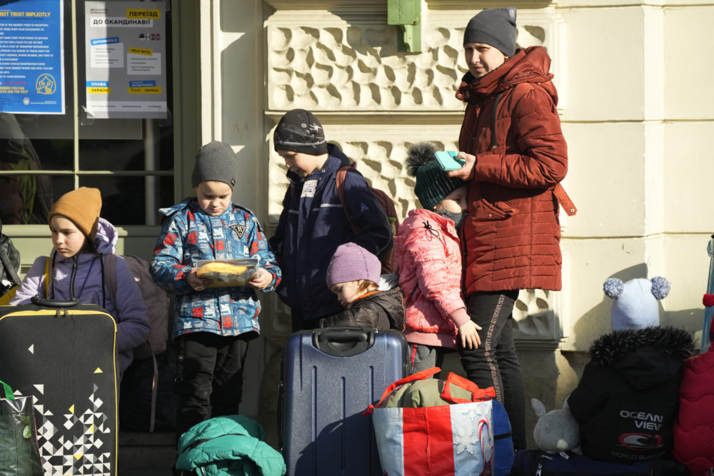 Refugees with children wait for a transport after fleeing the war from neighbouring Ukraine at a railway station in Przemysl, Poland, on Thursday, March 24, 2022. (AP Photo/Sergei Grits)